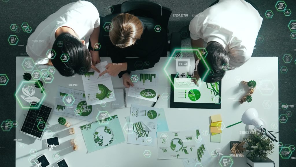 Top view of business team discussing about using clean energy and sustainable investment at meeting table with wind mill, document with environmental graph and holographic of eco power. Alimentation.